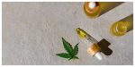 cannabis leaf and oil bottles with a droper on a grey surface