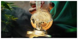 man inhaling from a glass bong, learning how to use a bong