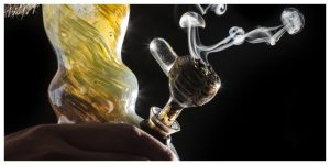 man smoking a glass bong in dark, comparing silicone bongs vs glass bongs